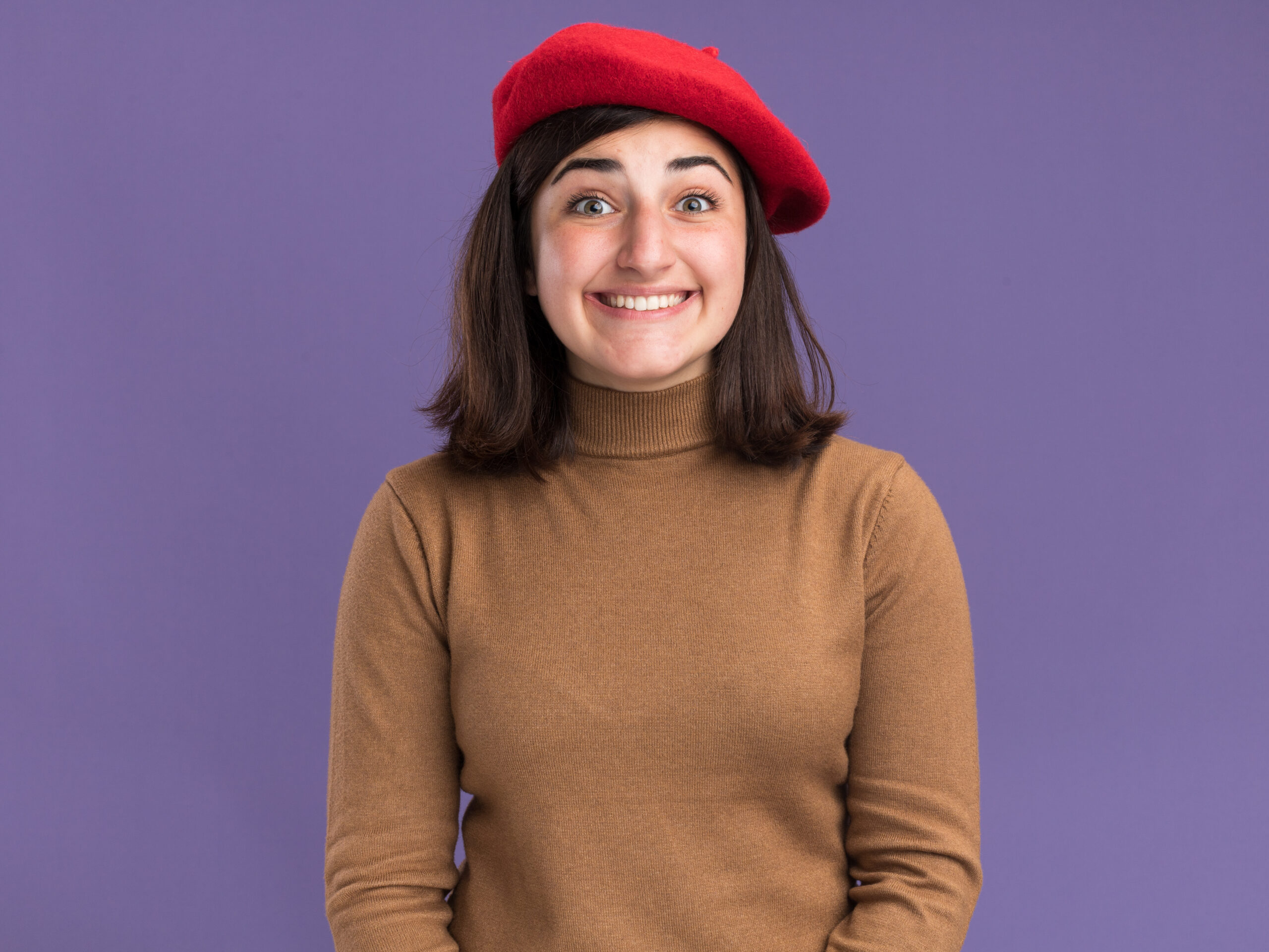 excited young pretty caucasian girl with beret hat looking at camera isolated on purple background with copy space